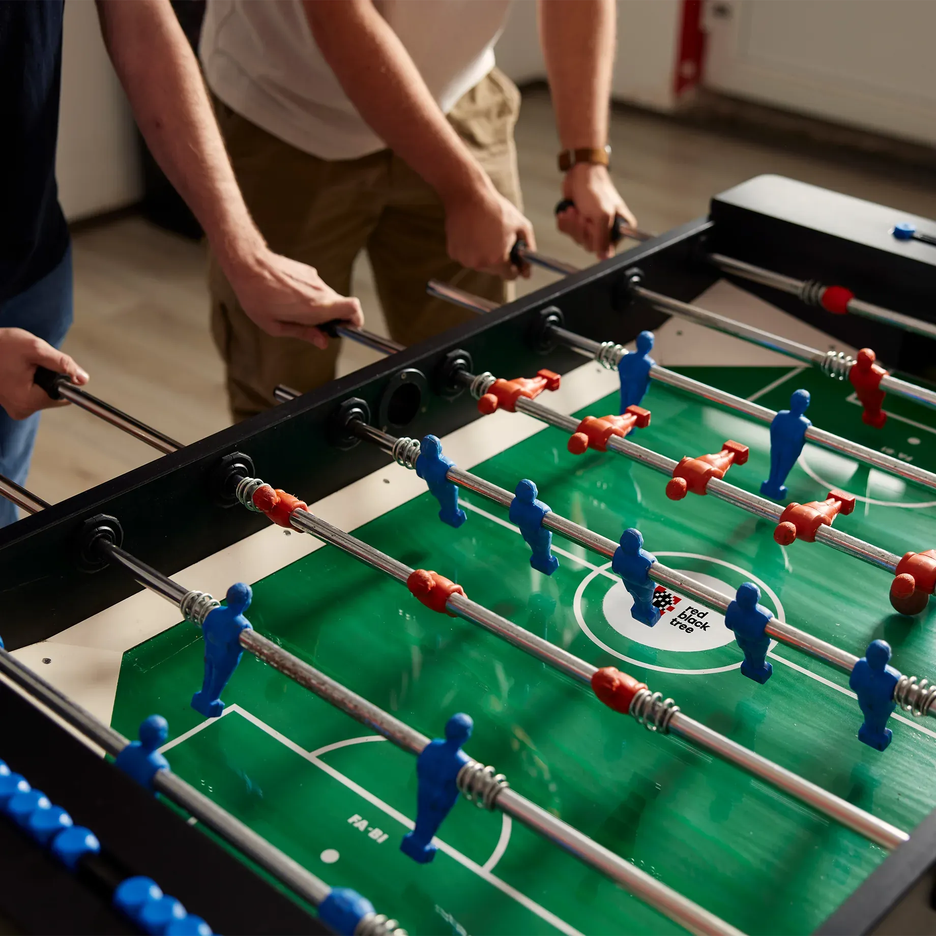 Foosball table, close up of people playing game in an office environment