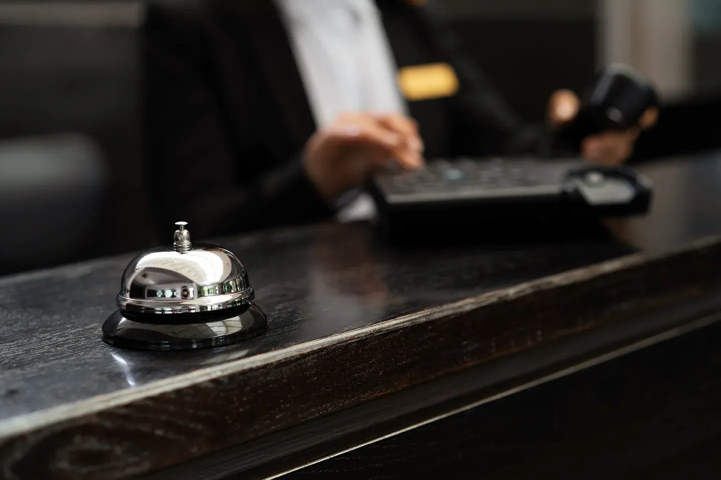 Close-up of a hotel reception desk with a bell and uniformed service staff ready to assist.