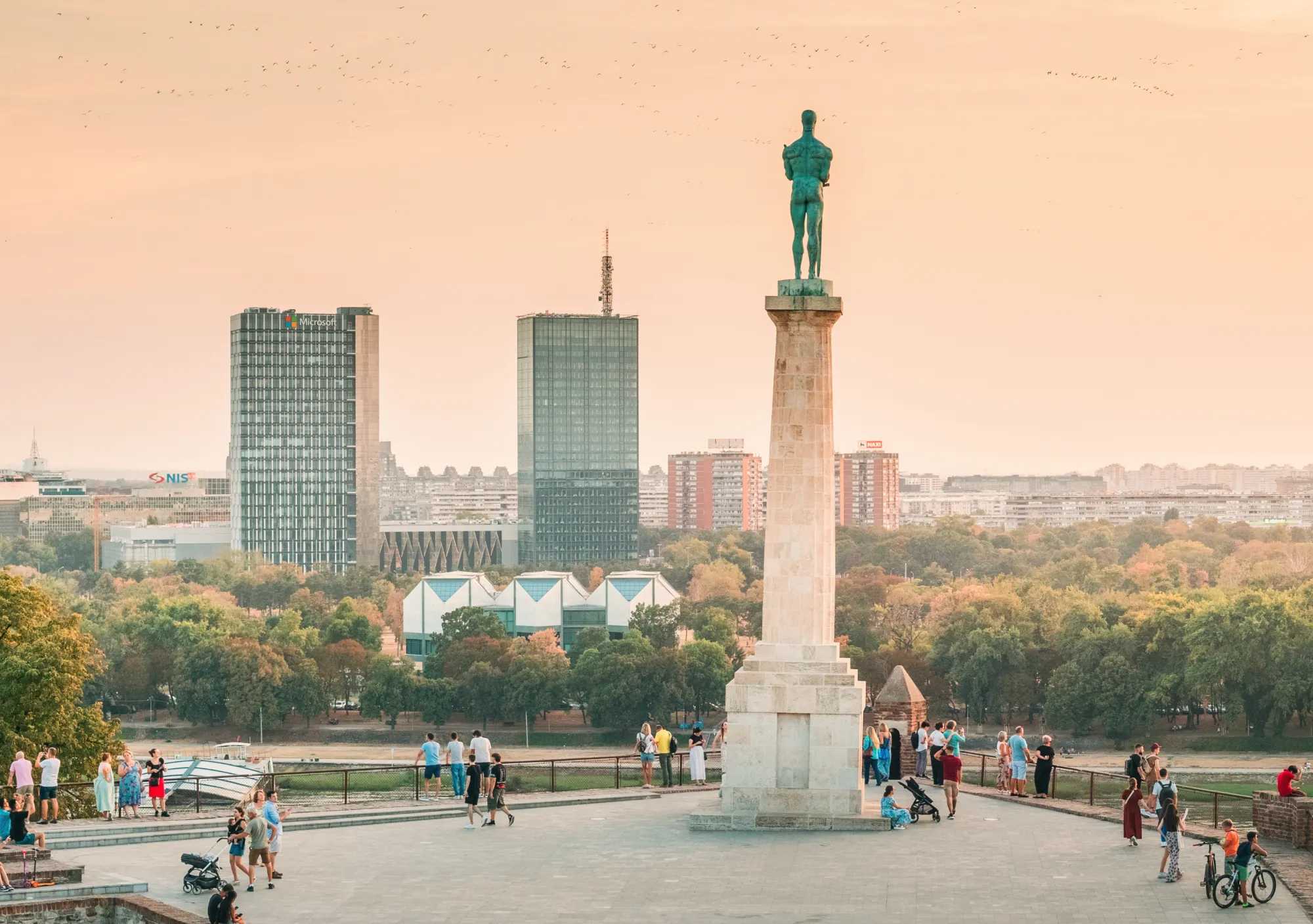 The Victor monument on Belgrade Fortress at sunset, with the towers of New Belgrade across the river.